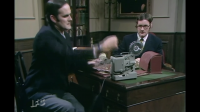 In this episode of Monty Python called Dinsdale John Cleese is pulling out a projector 8mm I assume but what brand is it? The take up reel on this turned counter clockwise.